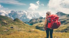 Woman with backpack enjoying mountains landscape view hiking