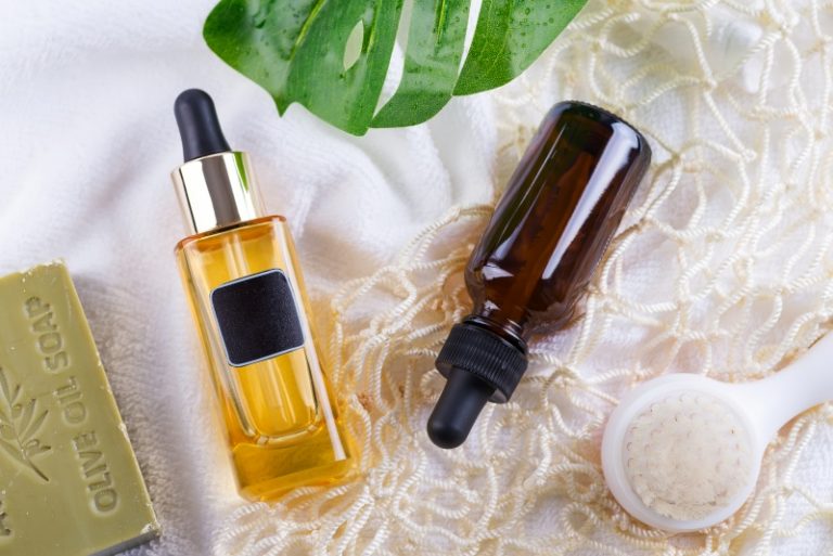 Cosmetic bottle with serum and hyaluronic acid , palm leaf, olive soap and Reusable shopping bags on a white towel